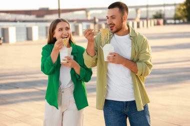 Öğle yemeği molasında sette Asya eriştesi yiyen genç bir çift.