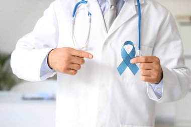 Erkek ürolog klinikteki mavi kurdeleyi işaret ediyor, yakın plan. Prostat kanseri farkındalığı