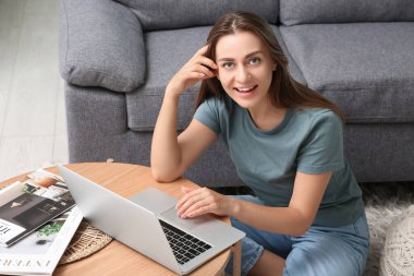 Evde dizüstü bilgisayar kullanan güzel bir kadın.