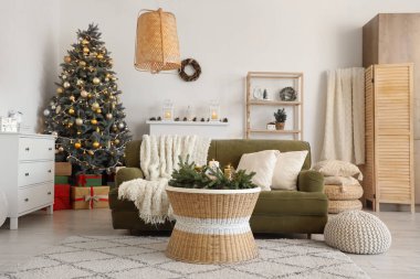 Oturma odasının içinde kanepe, Noel ağacı ve yanan mumlar var.