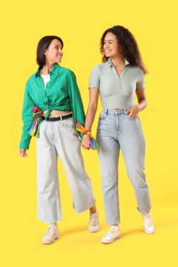 Sarı arka planda yürüyen genç lezbiyen çift