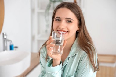 Banyoda su içen genç bir kadın, yakın plan.