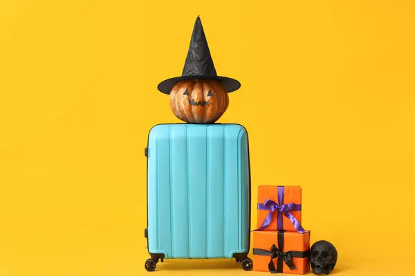 stock image Suitcase with different Halloween decorations and gift boxes on yellow background