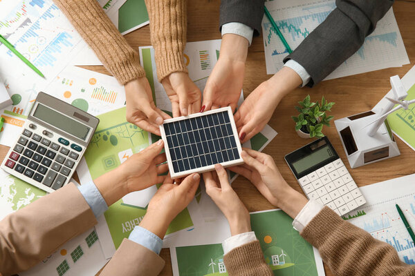 Бизнес-команда с солнечной панели работает над стратегиями зеленой энергии во время совещания в офисе, вид сверху
