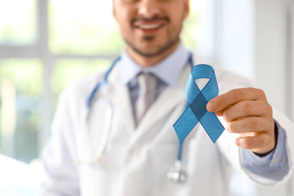 Male urologist with blue ribbon in clinic, closeup. Prostate cancer awareness concept