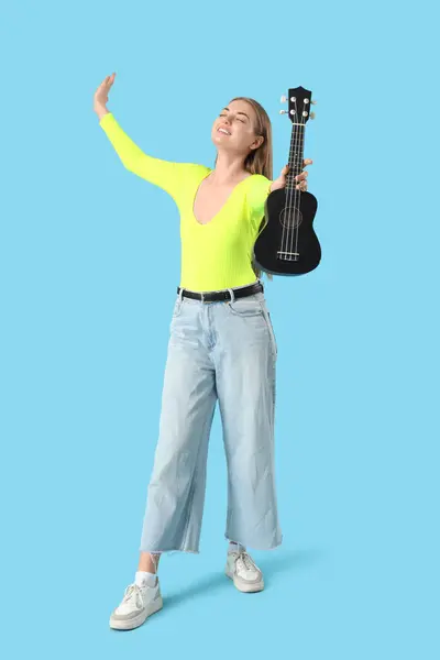 stock image Young woman with ukulele on blue background