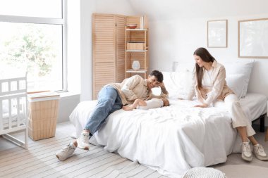 Genç ebeveynler ve küçük bebekleri yatak odasında uyuyor.