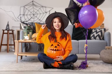 Cadılar Bayramı balkabağı ve balonlu cadı şapkalı genç Asyalı kadın.