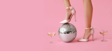 Yüksek topuklu ayakkabılı kadın bacakları, şampanya bardakları ve pembe arka planda disko topu ve mesaj için yer. Yeni yıl partisi konsepti