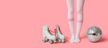 Klasik paten ve pembe arka planda disko topu olan genç bir kadının bacakları.