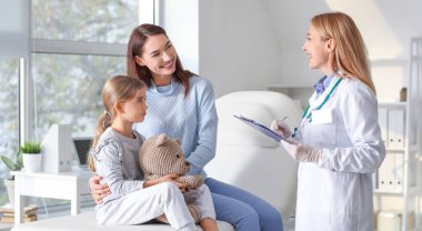 Küçük kızıyla birlikte bir kadın klinikteki çocuk doktorunu ziyaret ediyor.