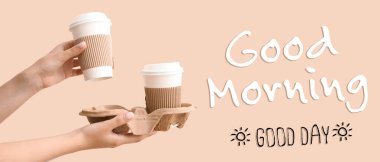 Female hands with takeaway paper cups and text GOOD MORNING GOOD DAY on beige background clipart