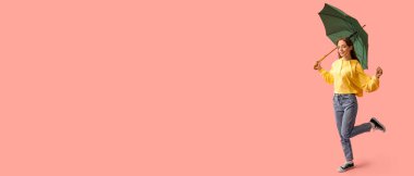 Şık sonbahar kıyafetleri içinde, pembe arka planda şemsiyesi olan güzel genç bir kadın.