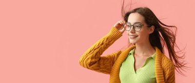 Pembe arka planda şık sonbahar kıyafetleri içinde güzel genç bir kadın. Mesaj için yeri var.