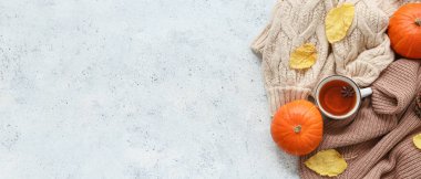 Bir fincan çay, sıcak süveterler, balkabakları ve sonbahar yapraklarıyla kompozisyon.