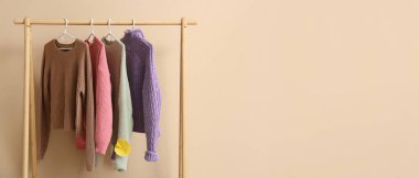 Süveter ve sonbahar yaprağıyla bej duvarın yanında dizilin. Tasarım için pankart