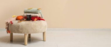 Sonbahar yapraklı süveterler, bej duvarın yanındaki puf üzerinde kahve ve kurabiyeler. Tasarım için pankart