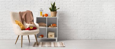 Odanın içinde raf ünitesi, sonbahar dekoru ve koltukta süveterler. Tasarım için pankart