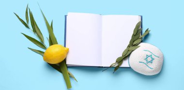 Dört tür (lulav, hadas, arava, etrog) Sukkot bayram sembolleri, kippah ve mavi arkaplan üzerine açık kitap