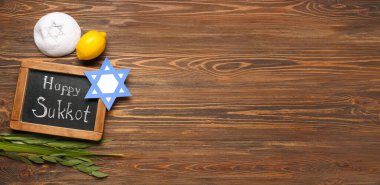 Dört tür (lulav, hadas, arava, etrog), kağıt David yıldızı, kippah ve yazı tahtası üzerinde HAPPY SUKKOT ve metin için alan