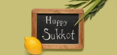 Dört tür (lulav, hadas, arava, etrog) ve yeşil arkaplanda Mutlu SUKKKOT yazılı kara tahta