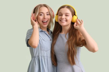 Yeşil arka planda kulaklık takan genç kız kardeşler.