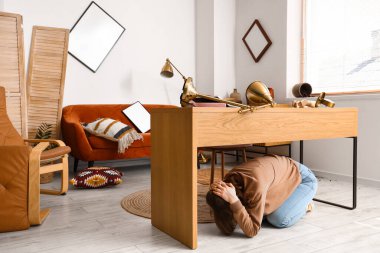 Deprem sırasında masanın altında saklanan genç kadın.