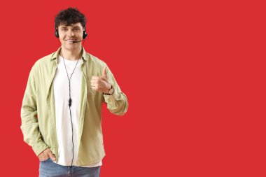 Erkek teknik destek ajanı kırmızı arka planda başparmak kaldırıyor