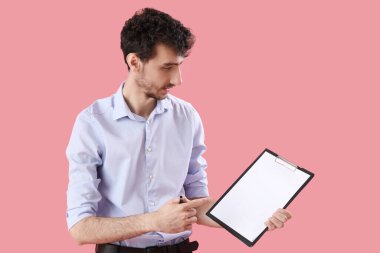 Pembe arka planda panosu olan genç bir iş adamı