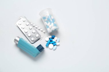 Astım ilacı ve gri arka planda haplarla dolu bir kutu.