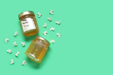 Yeşil zemin üzerinde akasya çiçekleri olan bal kavanozları