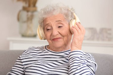 Evde kulaklıklı yaşlı kadın, yakın plan.