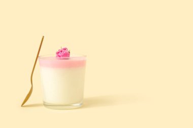 Bir bardak panna cotta ile bej arka planda güzel pembe bir gül çiçeği