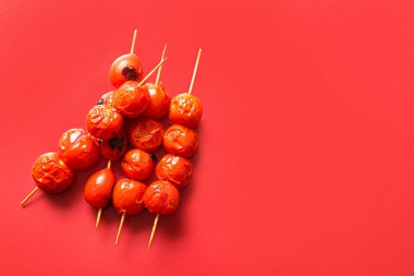Kırmızı arka planda lezzetli ızgara domatesli şişler.
