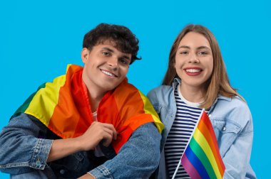 Mavi arka planda LGBT bayrakları olan genç çift