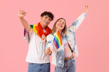 Pembe arka planda LGBT bayrakları olan mutlu genç bir çift.