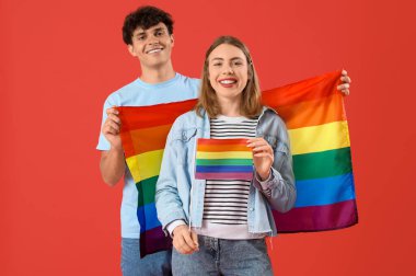 Kırmızı arka planda LGBT bayrakları olan genç bir çift