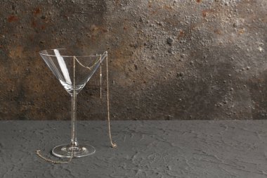 Siyah masanın üzerinde güzel zincirli kolye olan martini bardağı.