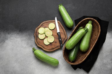 Gri arka planda taze yeşil kabaklı dilimler ve hasır çanak.