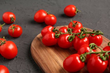 Siyah arka planda taze kiraz domatesli ahşap tahta.