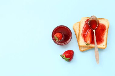 Mavi arka planda çilek reçelli lezzetli tostlar.