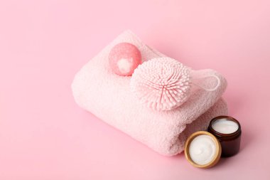 Temiz havlu, banyo bombası, sünger ve krem pembe arka planda.