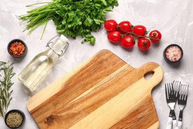 Ahşap kesim tahtası, taze baharatlar ve açık arkaplanda domatesler.