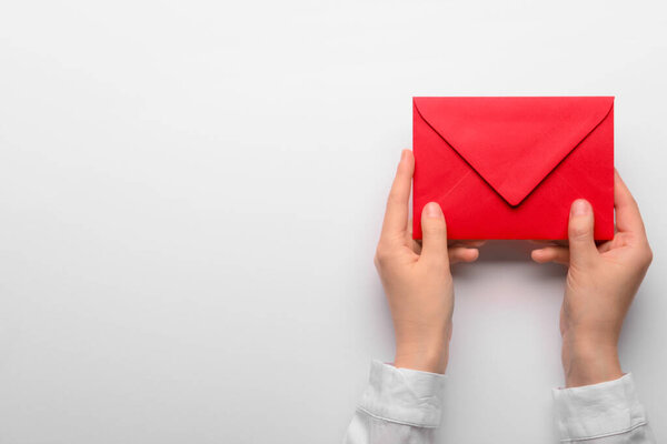 Female hands with red envelope on white background