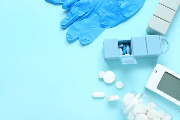 stock image Stethoscope, medical gloves, pillboxes and pills on blue background