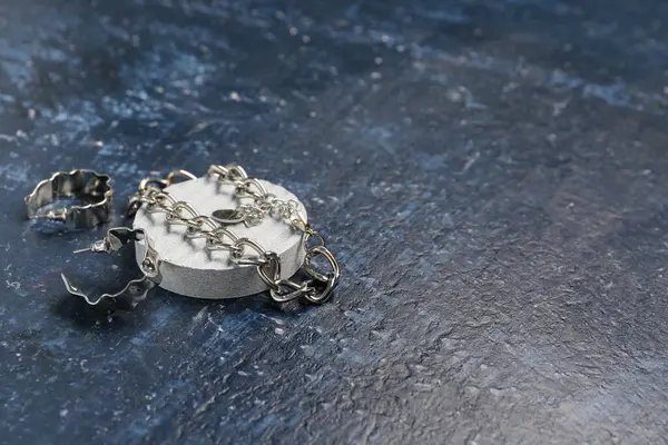 Gümüş küpeli dekoratif podyum ve grunge mavi arka planda kolye