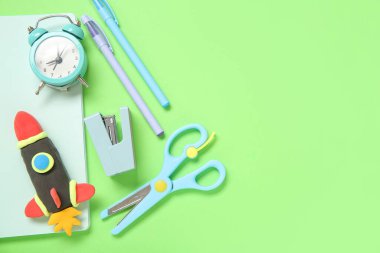 Yeşil arka planda farklı kırtasiye malzemeleriyle plastikten yapılmış roket