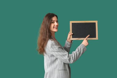 Yeşil arka planda tahtaya bakan kadın öğretmen