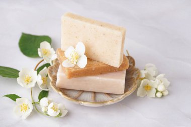 Bir yığın sabun ve arka planda güzel yasemin çiçekleri.