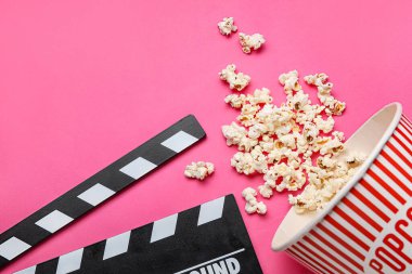 Kova lezzetli patlamış mısır ve pembe arka planda el çırpma tahtası